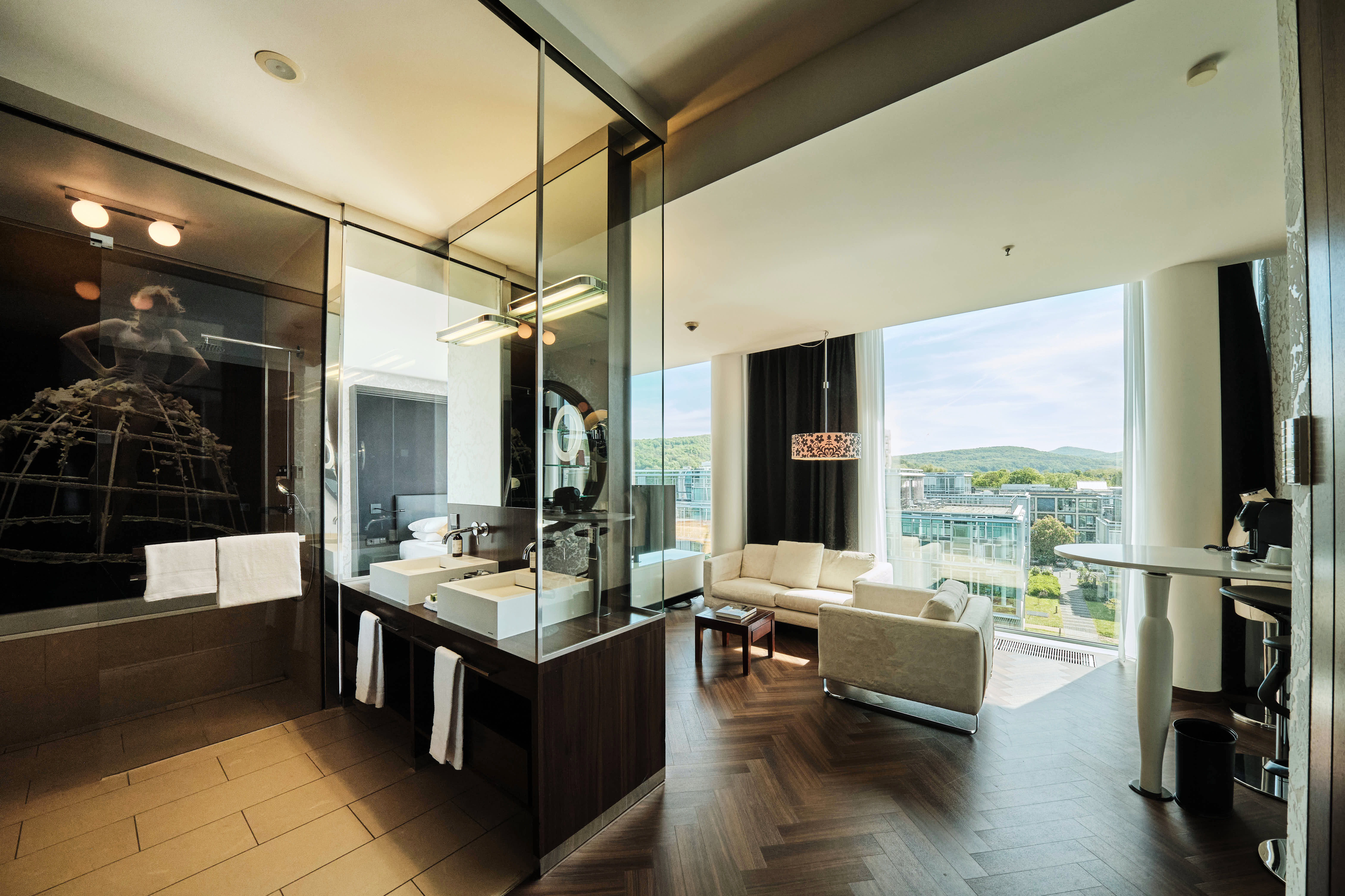 Badezimmer und Wohnzimmer mit Sofa und Stehtisch in der Junior Suite Deluxe.