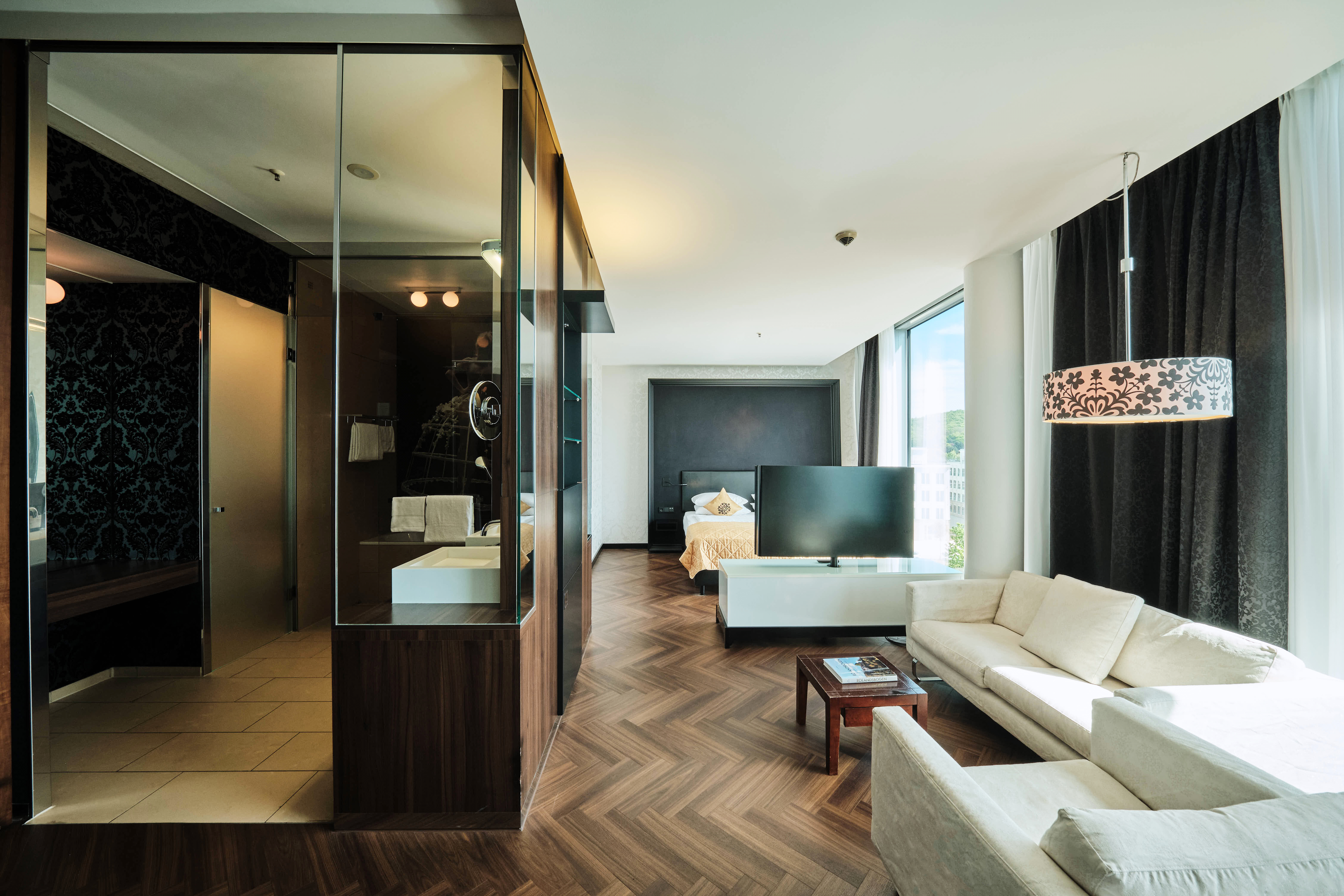 Wohnzimmer, Schlafzimmer und Badezimmer in der Junior Suite Deluxe. 